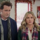 Ein Mann und eine Frau stehen in einem weihnachtlich dekorierten Raum mit roten Girlanden und Schleifen.