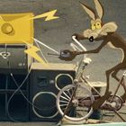 Zwei Lautsprecher mit Blitzmotiven; ein Cartoon-Wolf fährt Fahrrad, hält Fernbedienung, vor Lautsprechern.