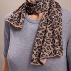Kein sichtbarer Text. Eine Person trägt einen grauen Pullover und einen Schal mit Leopardenmuster in Braun- und Schwarztönen.