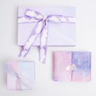 Drei Geschenke, eins mit lila Wolkenschleife, eins im bunten Papier mit Wolkensticker, eins mit Pastellstoffband.