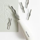 Text: "RICO DESIGN". Ein weißer Griff mit austauschbaren Metallklingen neben einer gravierten Herzform auf Papier.