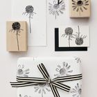 Schwarz-weiße Blumenzeichnungen auf Karten und Stempeln, Geschenk mit gestreifter Schleife verziert.