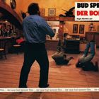 "Bud Spencer Der Bomber" in großem Text. Ein Mann steht, zwei liegen am Boden in einem rustikalen Raum mit Bar.