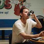 Die Texte "never grow up!" und "LOST & FOUND". Ein Mann trinkt aus einer Kaffeekanne und sitzt an einem Tisch.