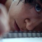 Keine sichtbaren Texte. Ein Auge fokussiert intensiv auf ein Notizbuch, Gesicht nahe an der Seite.