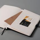 Eine Visitenkarte mit "TTZ Holzbau GmbH" und Adresse steckt in einem aufgeschlagenen Notizbuch.