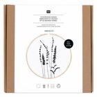 "STICKPACKUNG GRÄSER" steht über einem Stickrahmen mit schwarzer Stickerei von Gräsern; Verpackung aus braunem Karton.