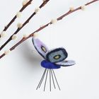 Ein bunter Filzschmetterling hängt an einem blühenden Weidenzweig.