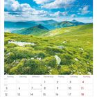 "Ich spüre das Wunder des Lebens und bin mittendrin." Zeigt eine grüne Berglandschaft unter blauem Himmel. Kalender April 2027.