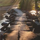 Kalender für März. Text: "Die Tarr Steps gehört zu den ältesten erhaltenen Steinplattenbrücken Europas." Sonnenstrahlen durch Bäume.