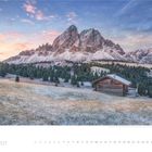 2 · 2027. Eine winterliche Landschaft mit einer Holzhütte vor beeindruckenden Bergen. Der Himmel zeigt rosa Wolken bei Sonnenaufgang.