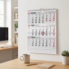 Wandkalender für Ende 2026 bis Anfang 2027 mit hervorgehobenem Datum. Moderne Büroeinrichtung mit Schreibtisch und Pflanzen.