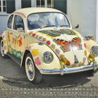 MÄRZ 2027 Kalender. Ein VW-Käfer mit bunten Blumen und Schmetterlingen bemalt, steht vor einem Haus.