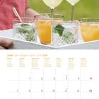 Kalenderseite Juni mit Wochentagen in mehreren Sprachen. Oben Getränke auf einem Tablett, darunter ein Kalender mit Daten.