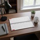 Kalender, 11. bis 17. Januar, Wochentage, Tisch, Lampe, Notizbuch, Stift, Pflanze, Tasse, Bücherregal im Hintergrund.
