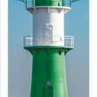 02. Monatskalender, Februar 2023. Grüner Leuchtturm am Meer auf einer felsigen Plattform.