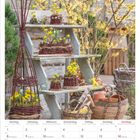 Kalenderblatt für Februar 2027 unten. Oben blühende gelbe Blumen in Weidenkörben auf hölzernen Regalen.