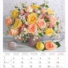 Kalender für März 2027 in mehreren Sprachen. Große Rosenblumen in Gelb und Orange in einer Vase.