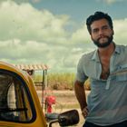 Es gibt keinen Text. Ein Mann lehnt entspannt an einem gelben Auto. Im Hintergrund sind Himmel und Landschaft.