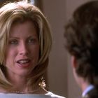 Es sind keine Texte sichtbar. Eine Frau mit blonden Haaren spricht mit einem Mann in einem Innenraum.