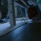 Ein Bein in Militärstiefeln steht auf einem Teppich mit Spielzeug, während ein Kind sich unter einem Bett versteckt.