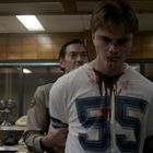 55 auf einem blutbefleckten weißen Trikot. Dahinter hält ein Mann in Uniform ihn fest. Im Hintergrund ein Schreibtisch.