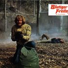 Aufschrift: "Blutiger Freitag". Szene im Wald: Ein Mann kniet mit Waffe, neben ihm eine liegende Person.