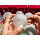 Eine Hand bemalt eine Weihnachtskugel mit Kamelmotiv; im Hintergrund rote Boxen.