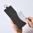 Visitenkarte mit "STUDIO EML" wird in ein dunkles Etui mit Schlüsselring gesteckt, gehalten von zwei Händen.