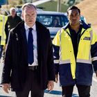 Männer in gelben Jacken mit "POLICE"-Abzeichen gehen auf einer Straße, gefolgt von weiteren uniformierten Personen.