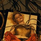 Ich kann keine Texte erkennen. Eine Person liegt auf einem Tisch, umgeben von Kabeln und Schläuchen. Orange-rotes Tuch.