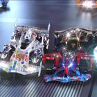 Illustration von futuristischen Rennwagen auf einer Rennstrecke, beleuchtet von kräftigen Scheinwerfern.