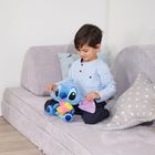 Ein Junge sitzt auf einem Sofa mit einem blauen Plüschtier in der Hand, umgeben von Kissen in Sternenmuster.