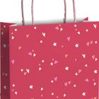 Eine rosafarbene Geschenktüte mit Herz- und Blumenmuster. Rosa Tragegriffe.