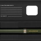 „In case of loss, please return to:“ steht auf einer schwarzen Verpackung mit Zeilen für Name und Belohnung. Ein grüner Stift mit „MOLESKINE“ liegt darin.