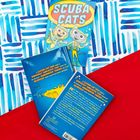 "SCUBA CATS" in großen Buchstaben. Zwei Katzen in Taucheranzügen. Hintergrund in Blau- und Rottönen, grafisches Muster.
