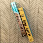 Zwei Bücher: "Karyn Parsons" und "Blue Beach", mit Muschel-Logo und Sandstrand. Im Hintergrund ein Zickzack-Muster.