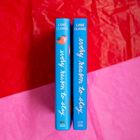 Buchrücken mit Text "every reason to stay" von Lane Clarke, auf blauem Hintergrund mit Erdbeersymbol. Hintergrund rot-pink.