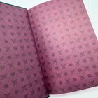 Keine Texte vorhanden. Lila Muster von gekreuzten Schwertern und Herzen auf offenem Buch, Licht von links.