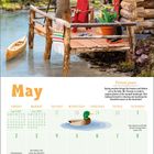 "Picture peace. Spring weather bringt Bootfahrer und Vogelliebhaber zum See. Mr. Peanuts ist bereit für Fotos der Landschaft."

Ein Eichhörnchen mit Kamera steht auf einem Steg neben einer Holzhütte am See. Ein Kalender für Mai ist unten.