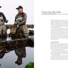 „Oysters from Bay to Bar: John Finger and Terry Sawyer, oyster farmers and marine biologists, Hog Island Oyster Co.“ Zwei Männer in Watthosen stehen lächelnd in einem Austernfarm-Becken, einer hält ein Netz voller Austern.