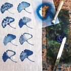 Zehn Textzeilen zu Drucktechniken; darunter sind mit blauer Farbe gedruckte Gingkoblätter auf Stoff. Daneben ein Pinsel.