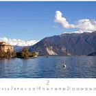 Kalendertext: Stresa, Casares Edition, Februar. Seepanorama mit Bergen, Gebäuden und blauem Himmel.