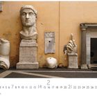 "Capitolinisches Museum" oben links. Große Steinskulpturen: Kopf, Hand und Fuß vor einer orangefarbenen Wand.