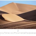Kalenderseite mit der Zahl 2 und Datumszahlen unten. Sanddünen unter klarem, blauem Himmel.