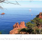 "Nordküste" und "CASARES EDITION"; Küstenlandschaft mit roter Felsformation, blauem Meer, Segelbooten und Bäumen.
