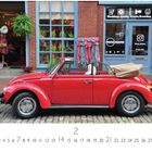 "VW Käfer Cabrio." Roter Oldtimer vor einem Geschäft; Schaufenster, bunte Kleidung, Kalenderdatum 2.