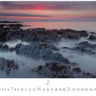 Text: "Schottland, Abendstimmung". Eine Küstenlandschaft mit Felsen und ruhigem Wasser bei Sonnenuntergang. Kalender für Februar.