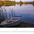"New Hampshire, Dawn at Lake." Ein Ruderboot liegt an einem ruhigen See, umgeben von Schilf und herbstlichem Wald.