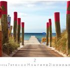 „Weg zum Meer“ steht unten geschrieben. Ein Holzsteg führt zwischen rot markierten Pfosten zum Strand mit blauem Meer.